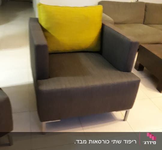 כורסה אפורה עם כרית צהובה על רגלי מתכת